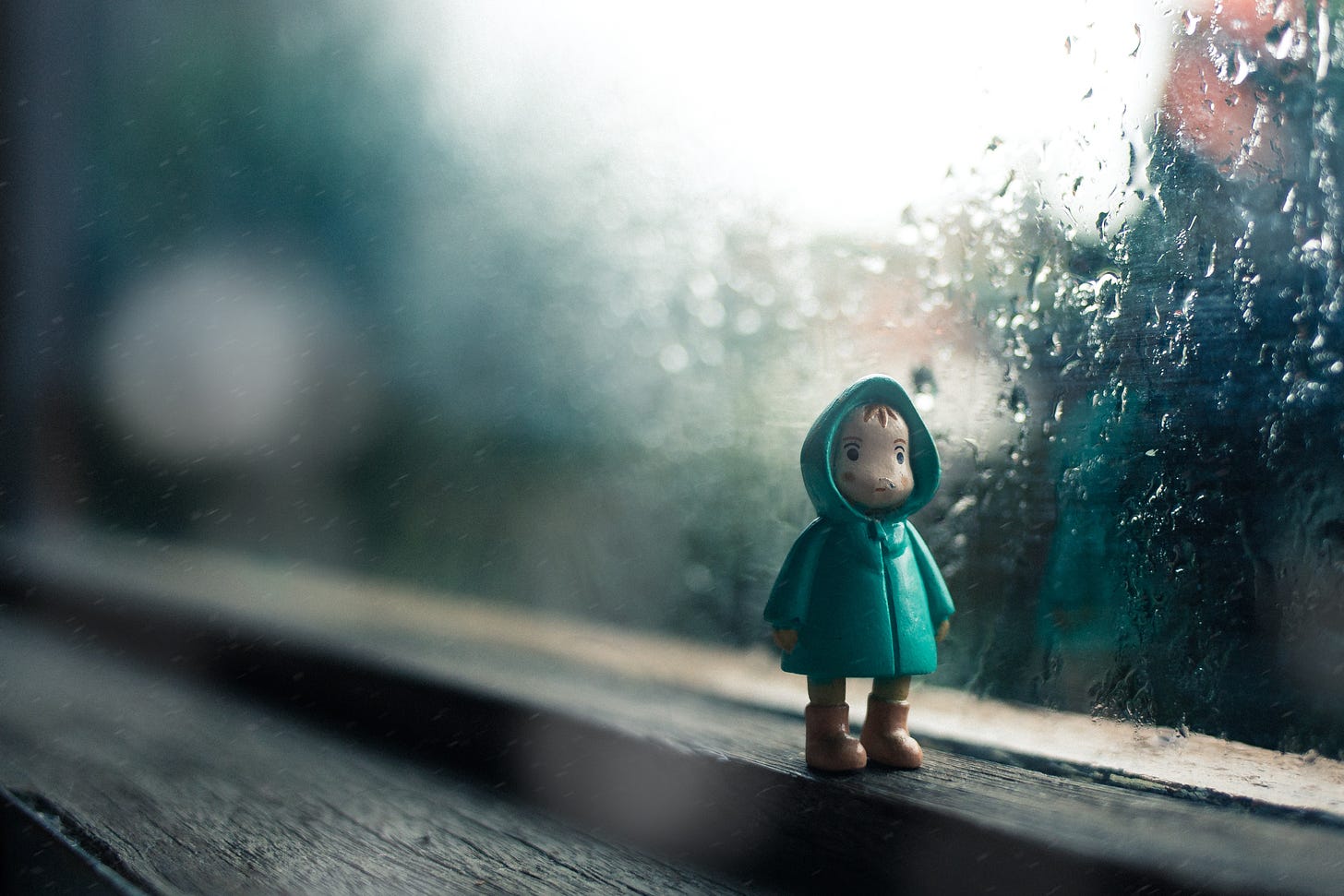 kid wearing green jacket mini figure beside glass window photo