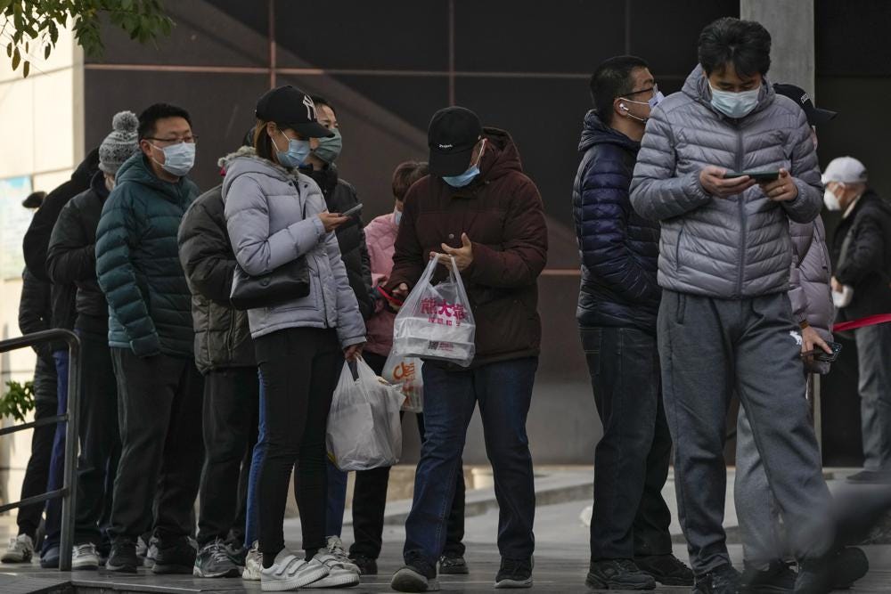 Residents stand in line to enter a store which controls the flow of shoppers in Beijing, Sunday, Nov. 27, 2022. Protests against China's strict zero-COVID policies in Shanghai continued on Saturday afternoon, after police cleared away hundreds of protesters in the early morning hours with force and pepper spray. (AP Photo/Andy Wong)
