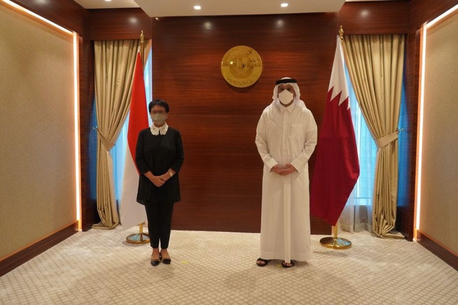 Two people in white robes in a room with flags

Description automatically generated with low confidence