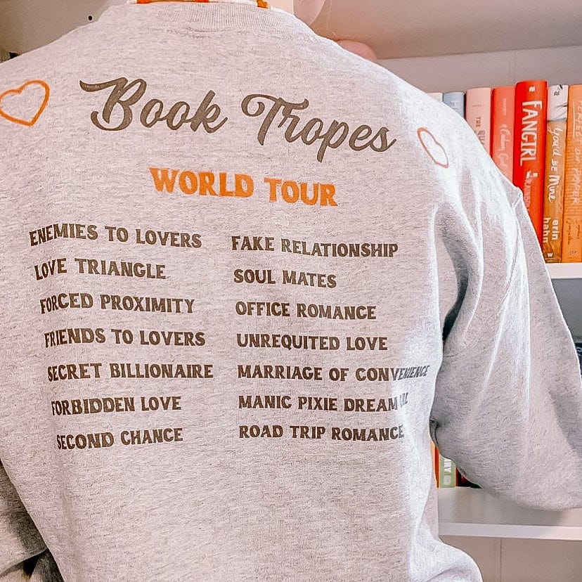 Sweatshirt one can buy on Etsy that lists off popular Book Tropes as if it were a performing artist and had a World Tour.