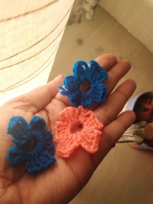 A hand holding three flowers crocheted.