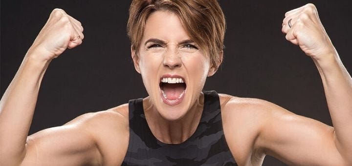 Amanda Thebe flexing her arms with her mouth open, looking fierce