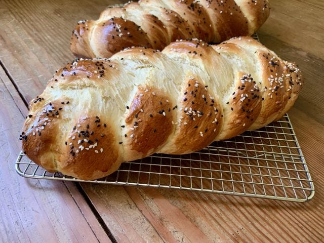 A loaf of braided bread sprinkled with black and white sesame seeds on top.