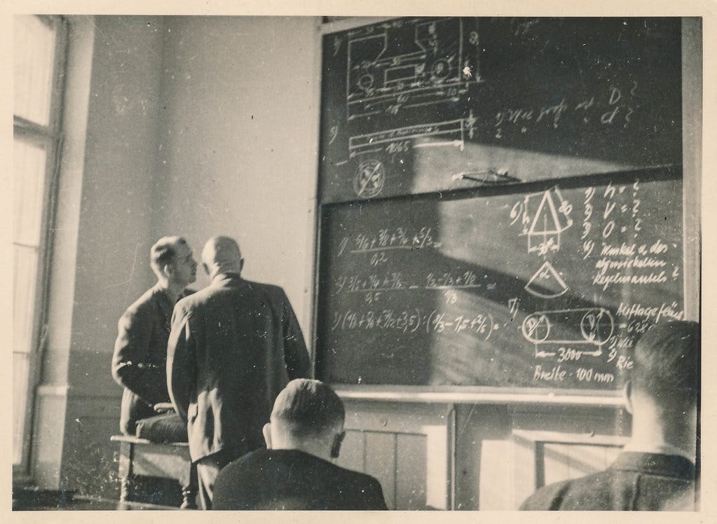 Students study an equation on a chalk board
