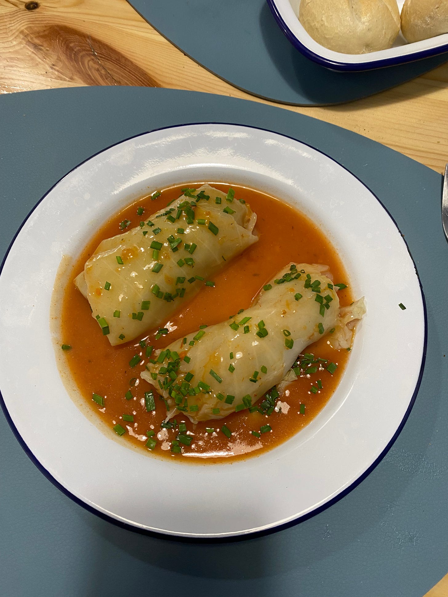 A bowl of cabbage rolls stuffed with rice in a sauce.