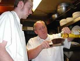 Older chef (right) shows younger chef how to clean