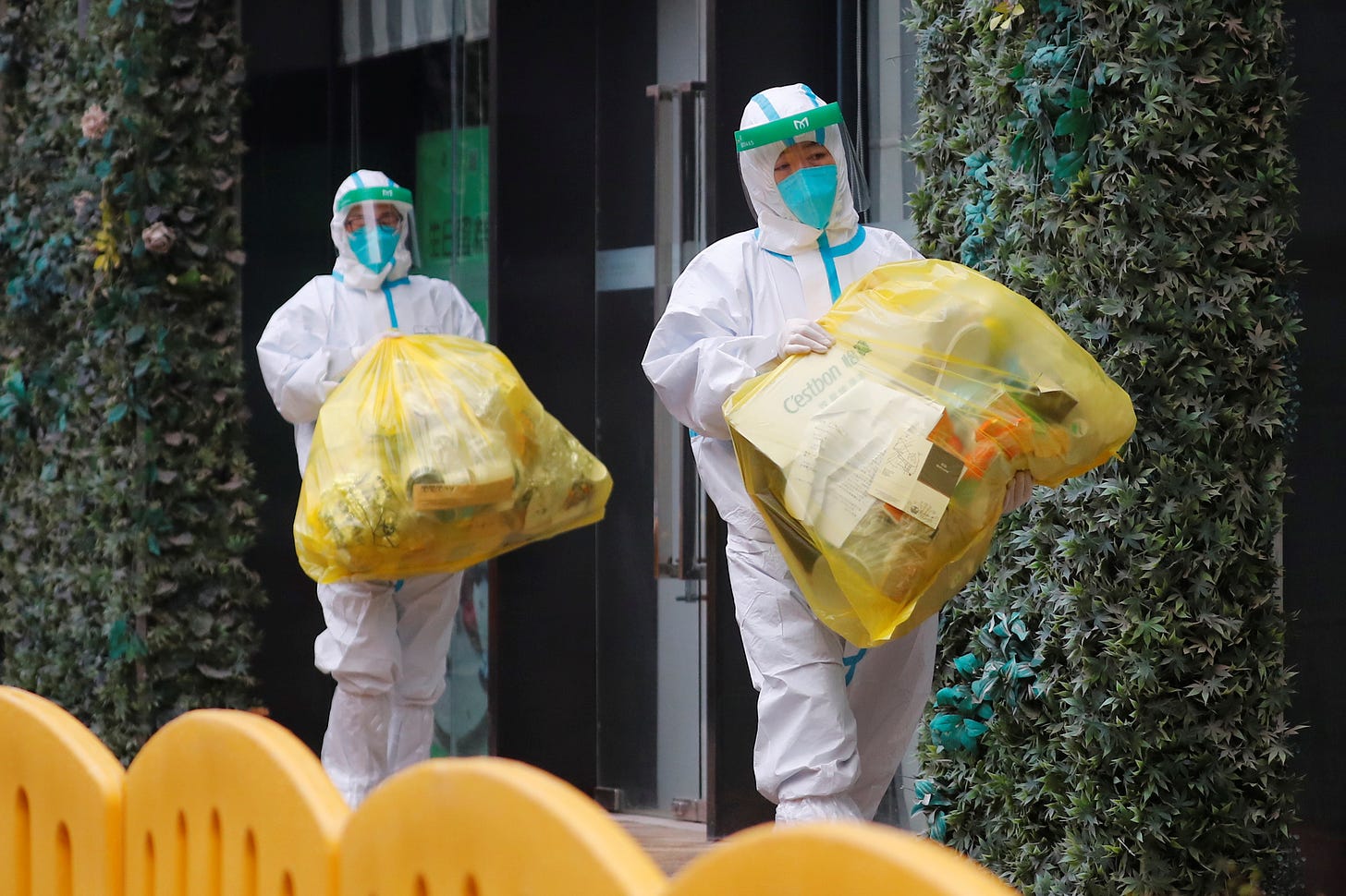 People in protective suits walk outside a hotel in Wuhan