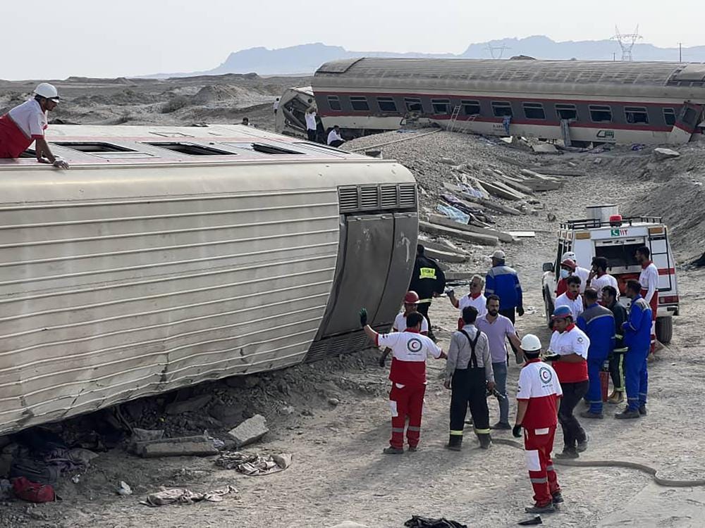 In this photo provided by Iranian Red Crescent Society, rescuers work at the scene where a passenger train partially derailed near the desert city of Tabas in eastern Iran, Wednesday, June 8, 2022. (Iranian Red Crescent Society via AP)