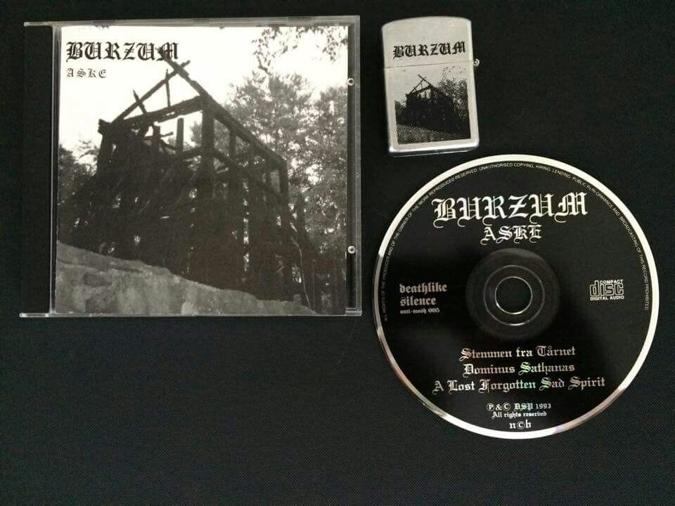The jewel case and CD for Burzum's EP Aske, with a matching zippo lighter. They're all in black, white, and silver.