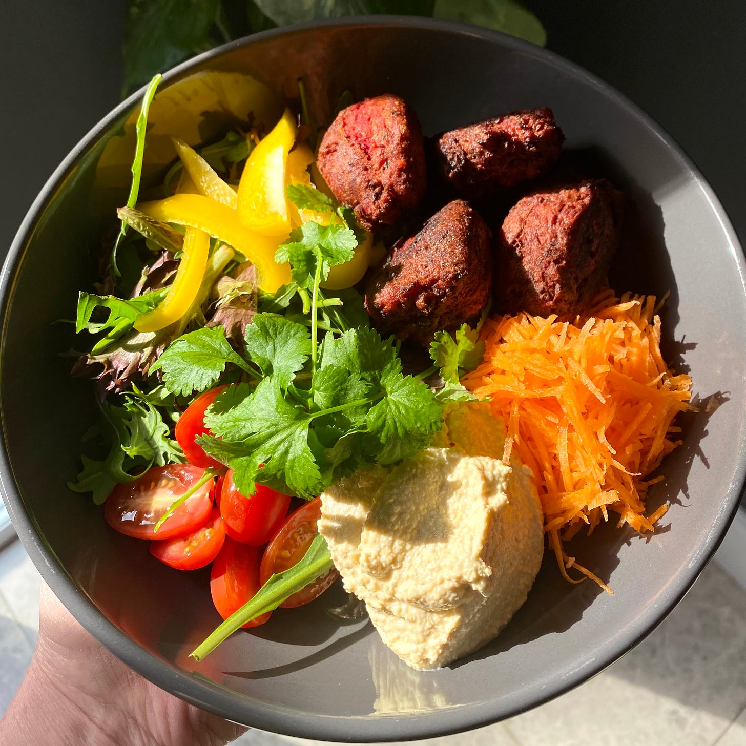 Bowl of falafel, peppers, carrot, tomato, lettuce and houmous