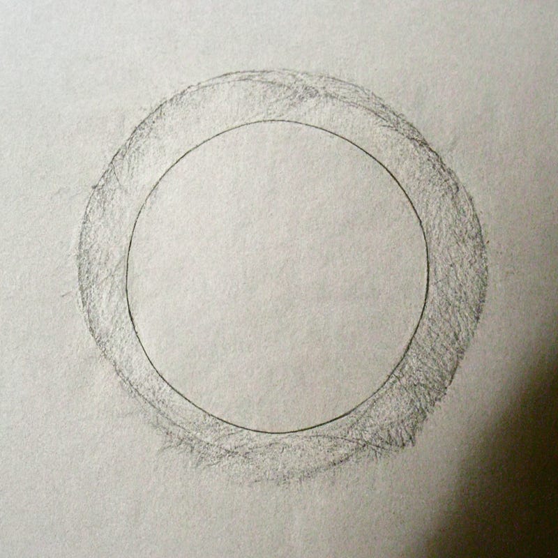 A think pencil circle on white paper, surrounded by a softer pencil circle that looks like someone might have done a pencil-rub on the bottom of a coffee mug. A dark shadow covers the bottom right corner of the paper.
