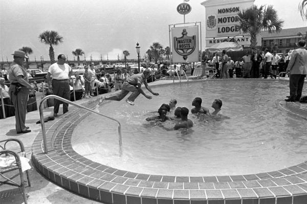 A white police officer in plain clothes jumps in to arrest protesters integrating a pool in 1964. Credit...Horace Cort/Associated Press