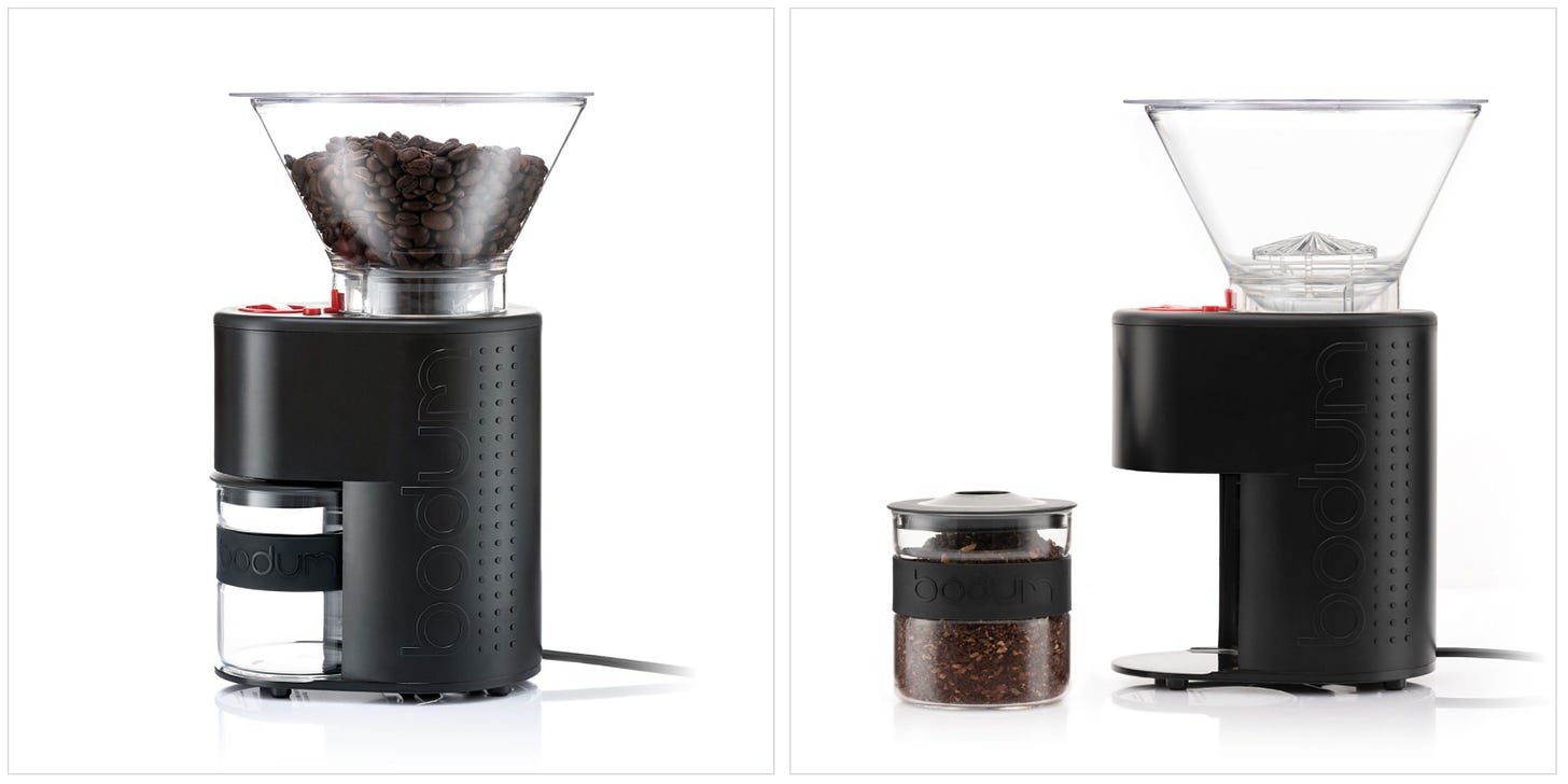 A side view of a black countertop coffee grinder with a clear hopper filled with coffee beans, red accent buttons and a glass container to catch the coffee bean grinds fitted below the grinder.