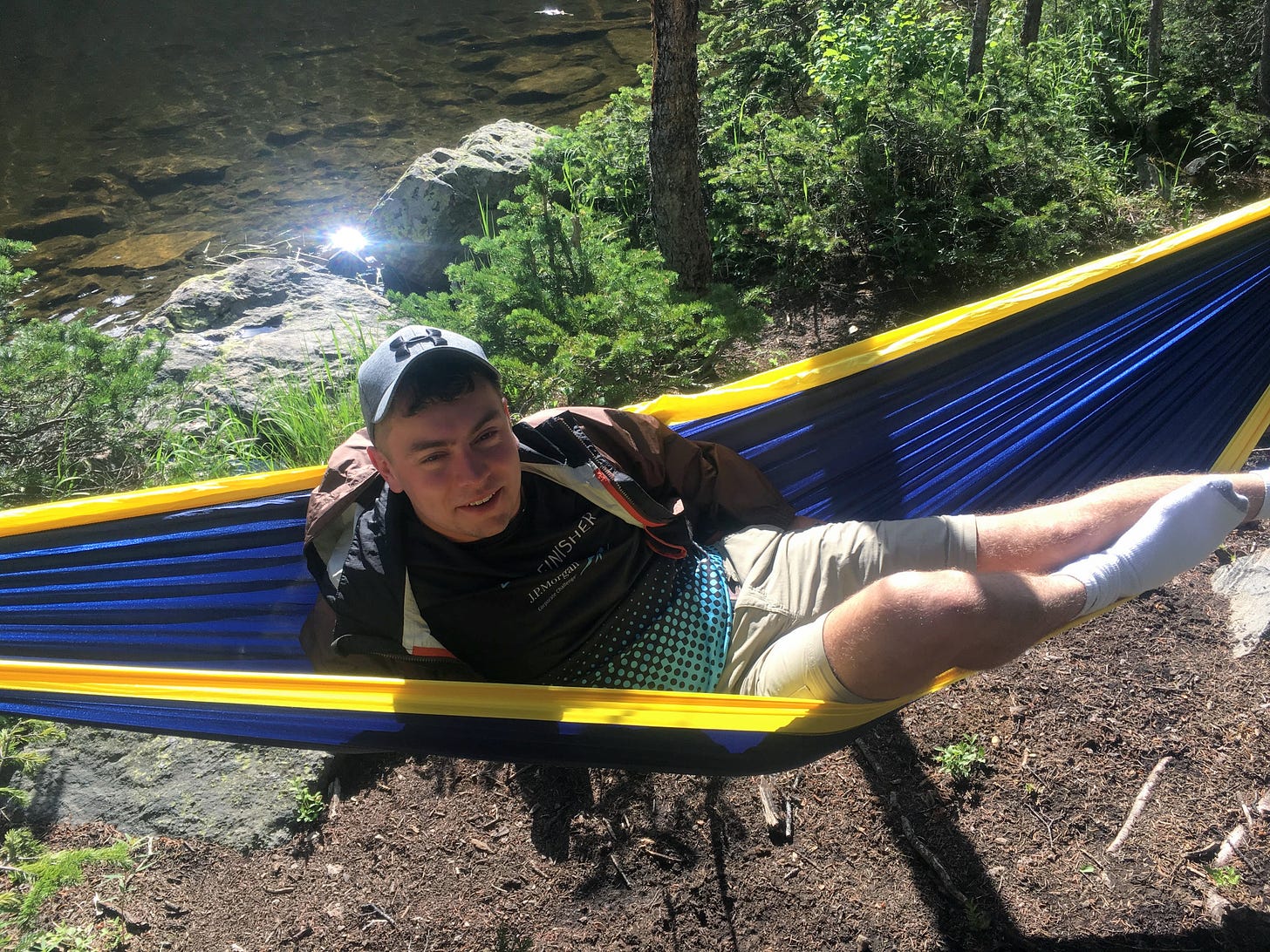 Me, lounging in a blue and yellow hammock by the side of a mountain lake