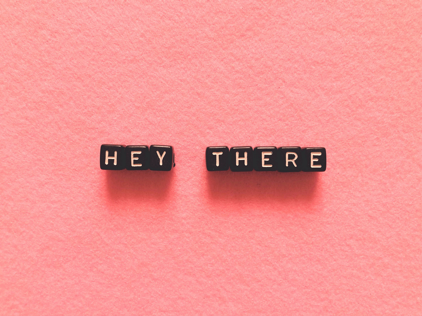 Black letters read, “Hey, there” against a pink background.
