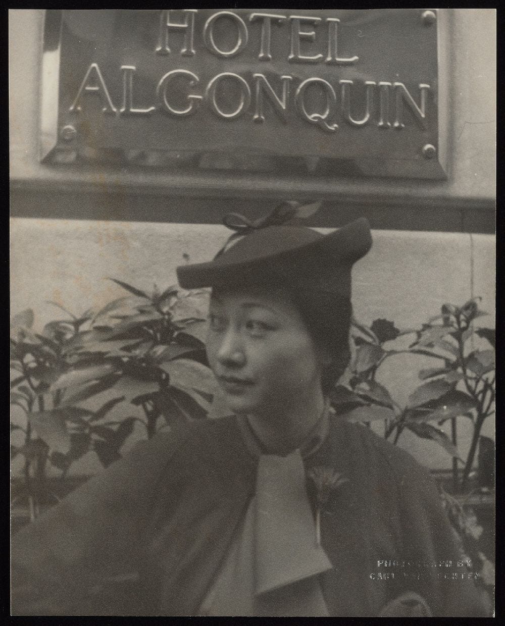 Anna May Wong looking spiffy in her hat, scarf, and a fresh flower pinned to her coat at the Algonquin Hotel, where she often stayed on trips to New York City.