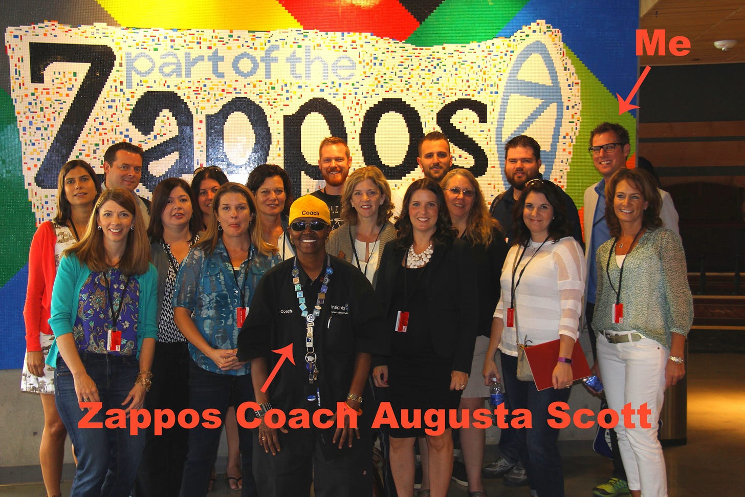 A group of smiling attendees in front of a giant zappos sign made out of legos.