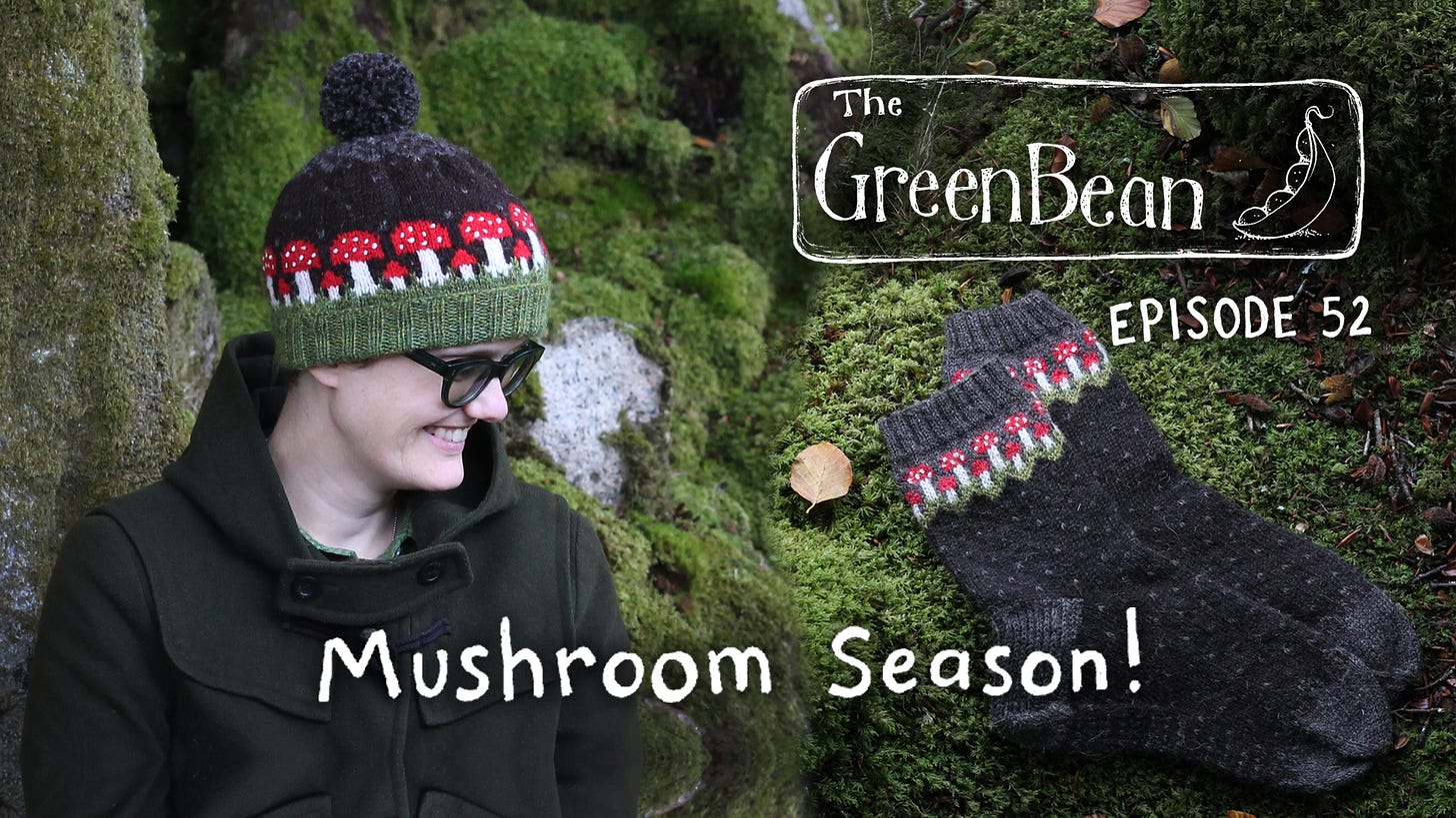 Image description: title card for episode 52 of The Green Bean podcast. On the left, Katie - a white human with glasses - is sitting in a mossy nook wearing a dark green duffle coat and woolly hat with colourwork fly agaric mushrooms. To the right, a pair of sock is lying in the moss, showing the same mushroom motif around the ankle. Over the top of these photos in white is The Green Bean Podcast logo, Episode 52, and the title: Mushroom Season!
