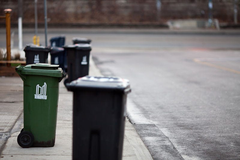 Toronto garbage and green bins on a sidewalk.