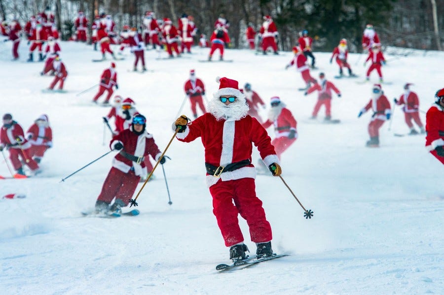 Dozens of people dressed as Santa Claus ski down a hillside.