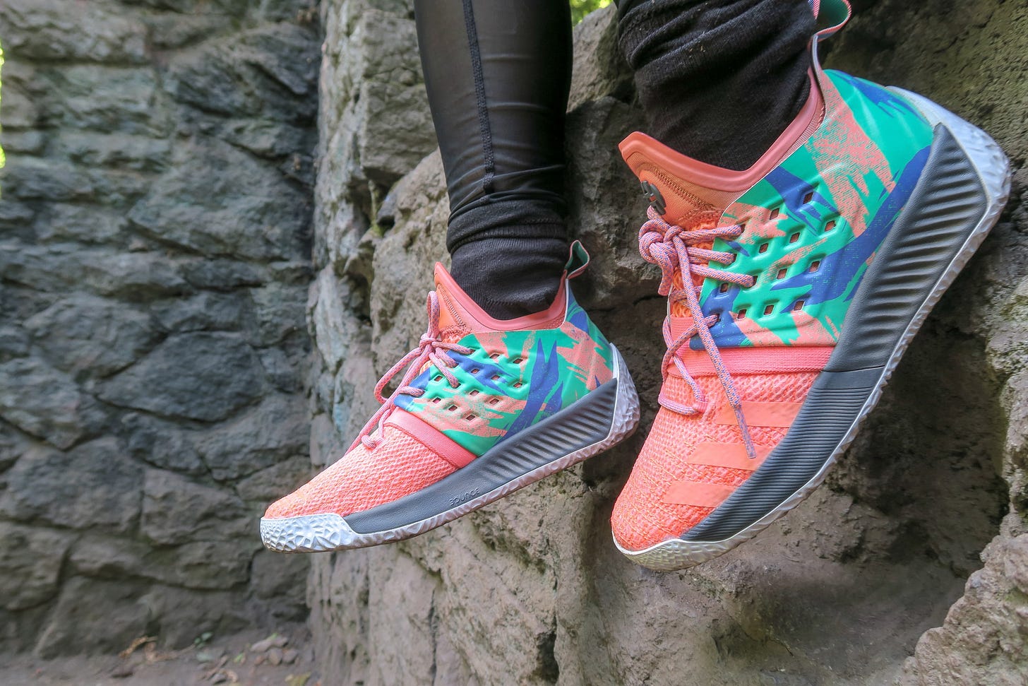 a person sitting on a rock outcrop, wearing bright colored sneakers