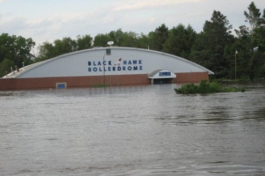 A large building submerged under several feet of water, up to the tops of its doors.