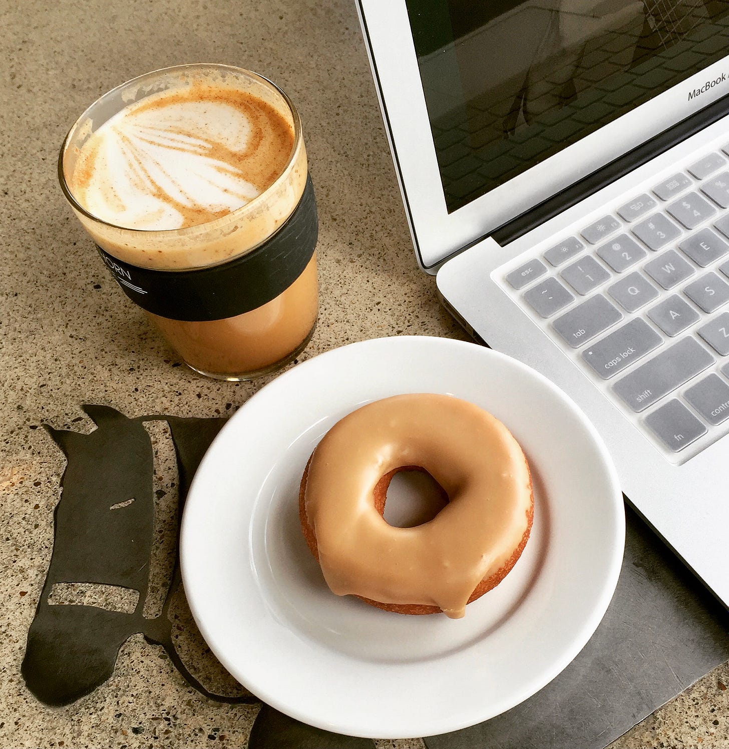 iced coffee and donut on table near laptop