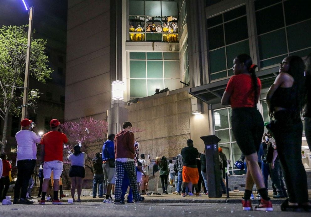 PHOTO: Onlookers watch from the street as inmates chant and throw things from broken windows at the St. Louis Justice Center, known as the city jail, April 4, 2021. 