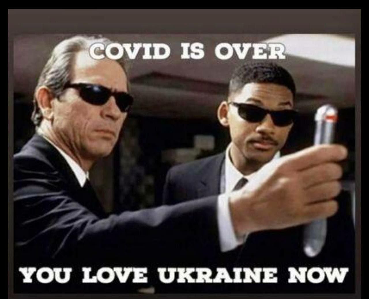 Image: Two Government agents hold up a memory eraser. Top text reads “COVID is over” Bottom Text “You love Ukraine now”