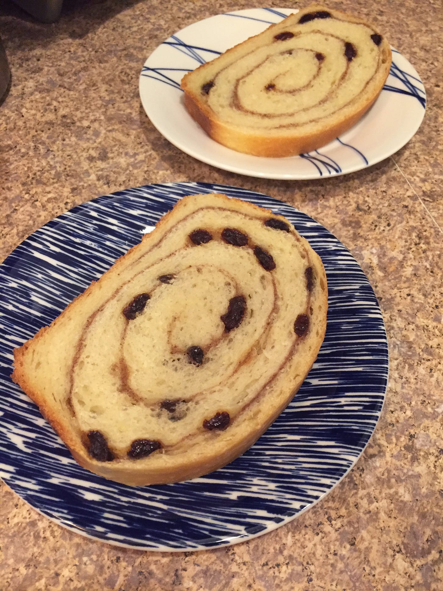 on blue and white plates, two slices of cinnamon-raisin bread. The swirl pattern of the filling is dotted with raisins, and the bread is airy and light.