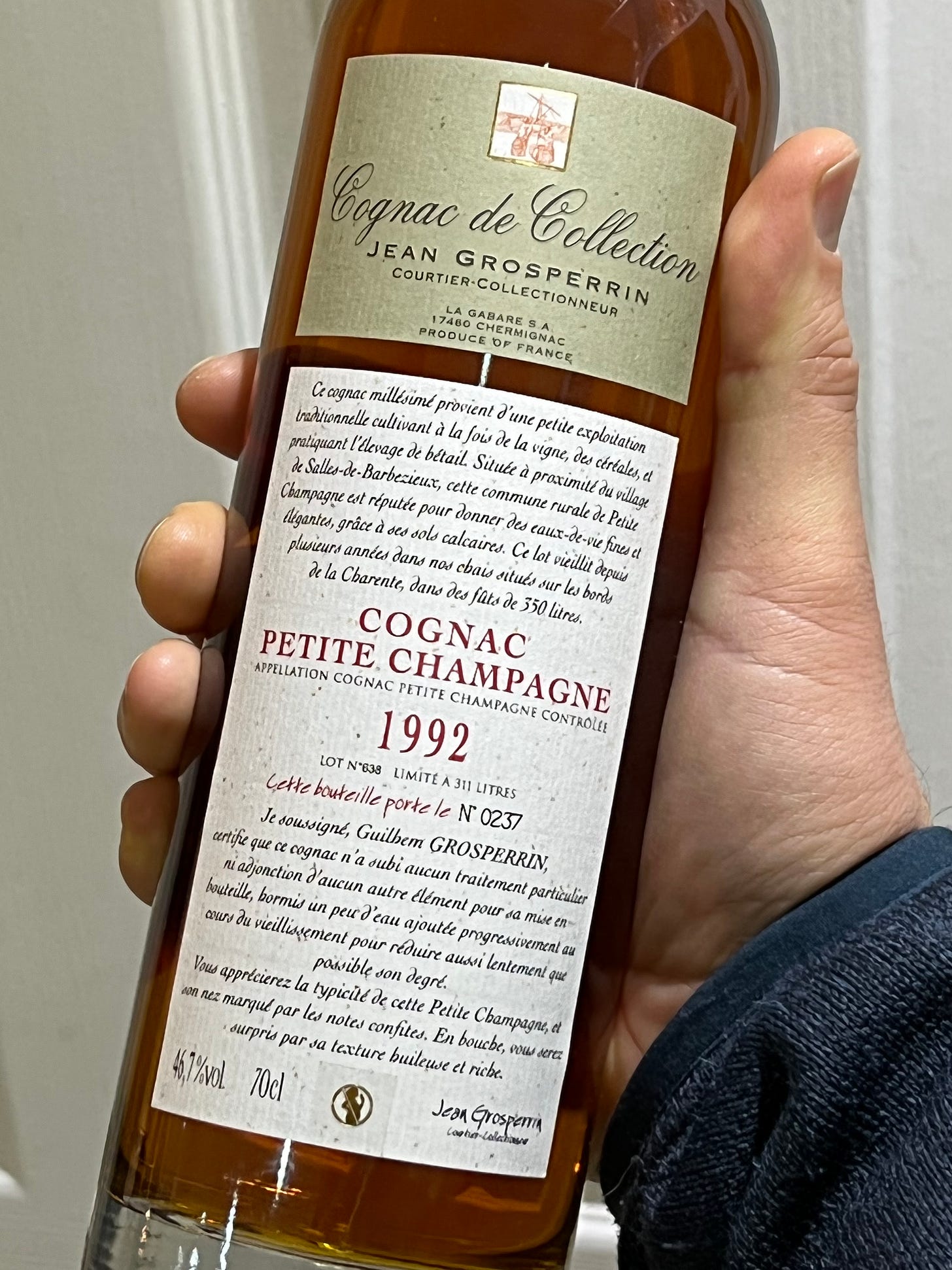A bottle of 1992 Cognac is held up in a hand