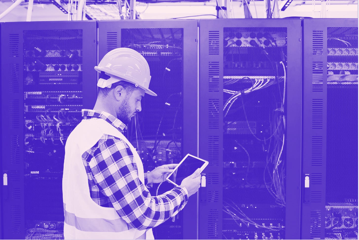 A man checking data center infrastructure in a hard hat.