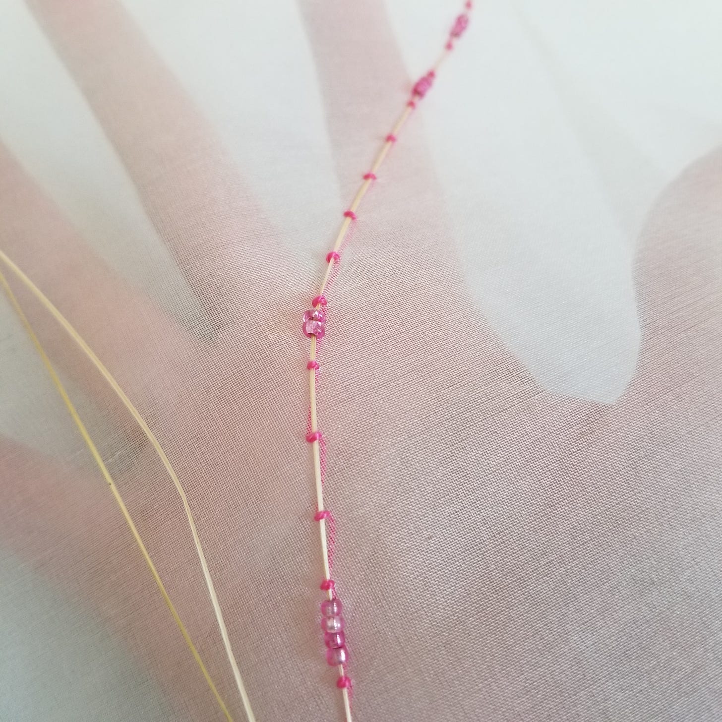 Dried grass couched to silk organza with pink thread and pink glass beads