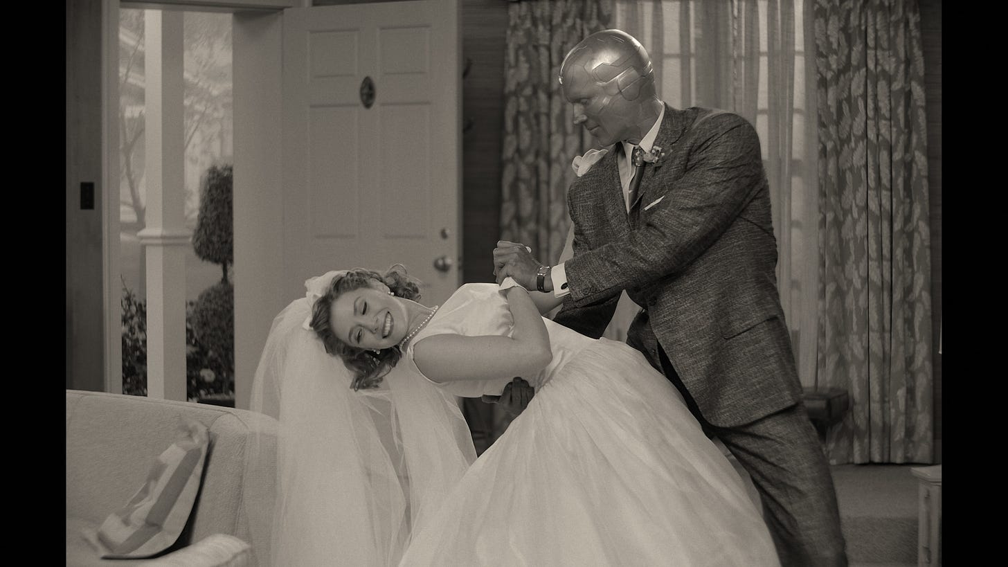 Image of Wanda in wedding dress being dipped by Vision who is wearing a 3-piece suit. Black and white image