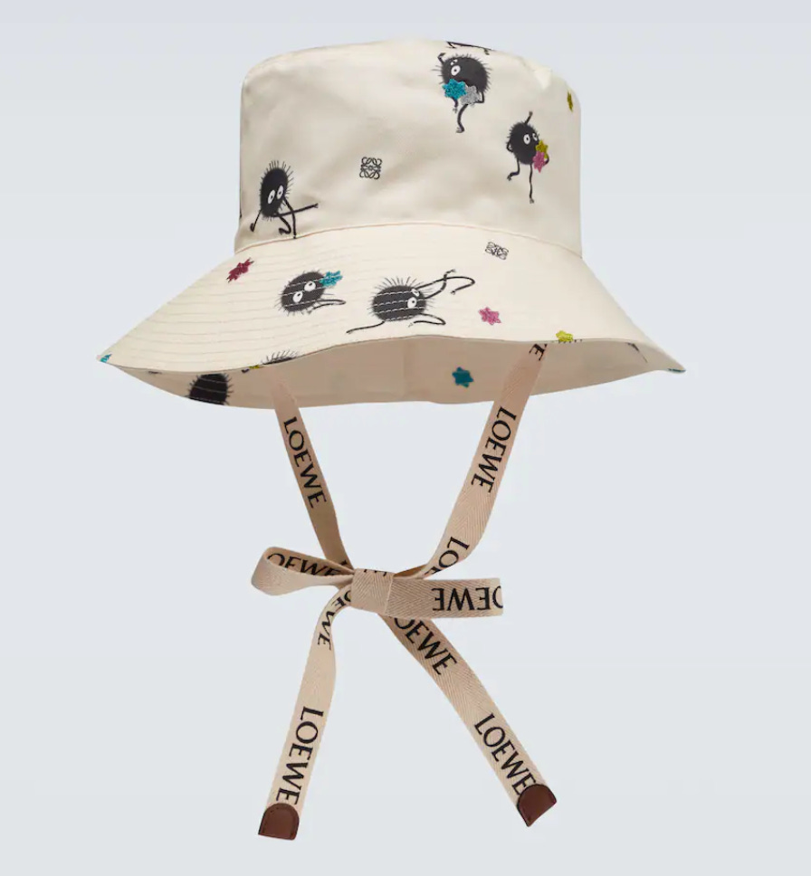 A product photo of a Loewe x Ghibli cream bucket hat, with little black sootyball characters dotted over it.