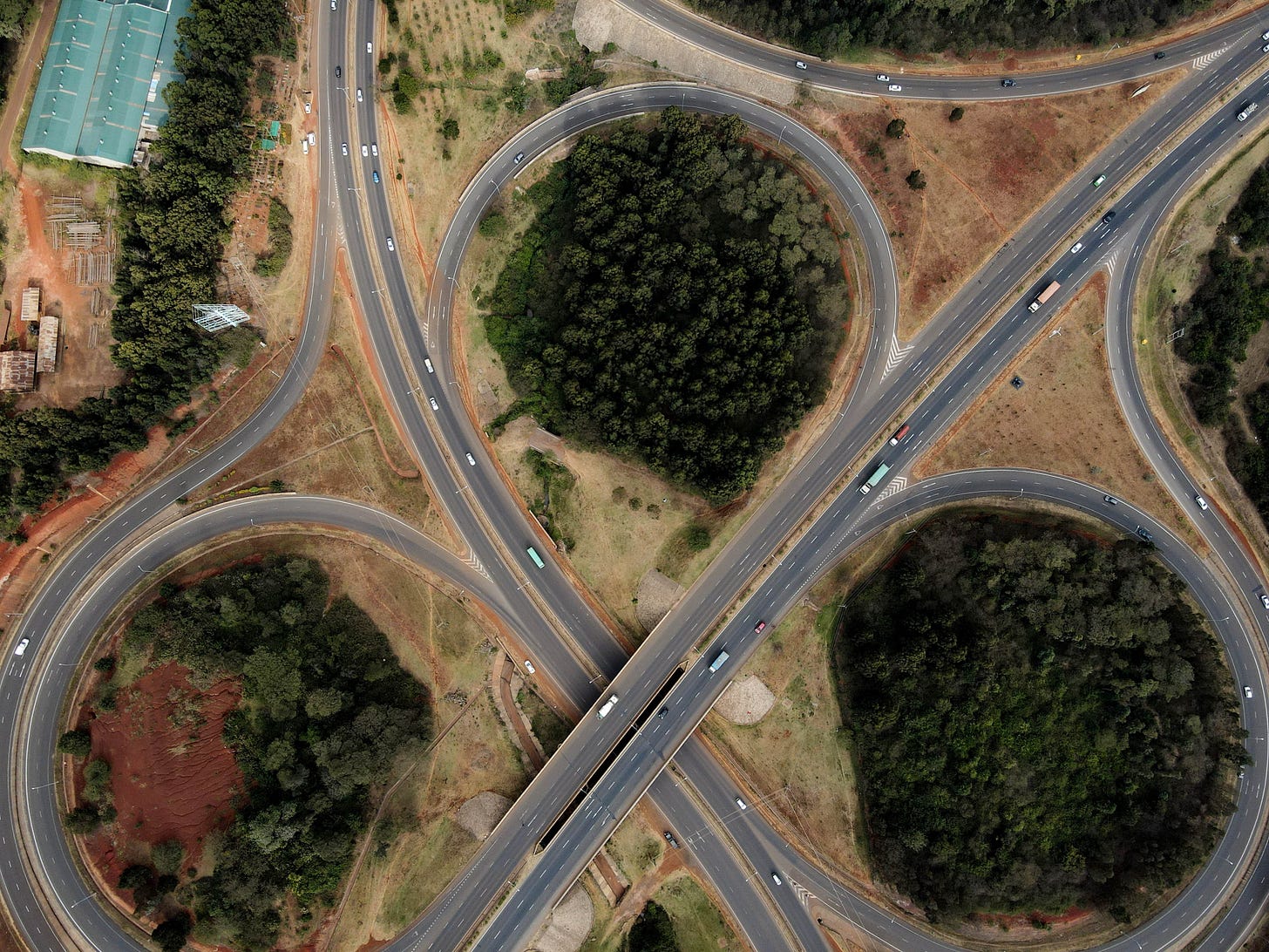 A cloverleaf highway design with clumps of trees in between.