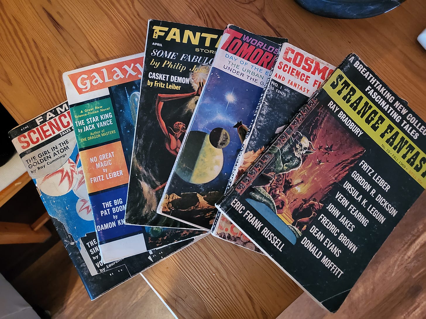 An array of science fiction magazines from the 50s and 60s spread out on a wooden table