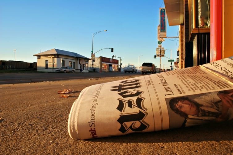 Newspaper lying on ground in country town.