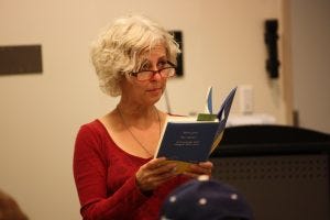 Photo of Kate DiCamillo standing and holding a book.