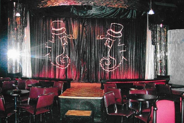 The stage of the Seahorse. On a stage curtain, two seahorses in top hats face each other. The bar is empty.