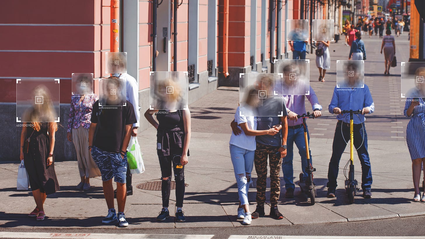 People stand on a street corner with their faces obscured by gray boxes indicating a biometric data system engaging in facial analysis.
