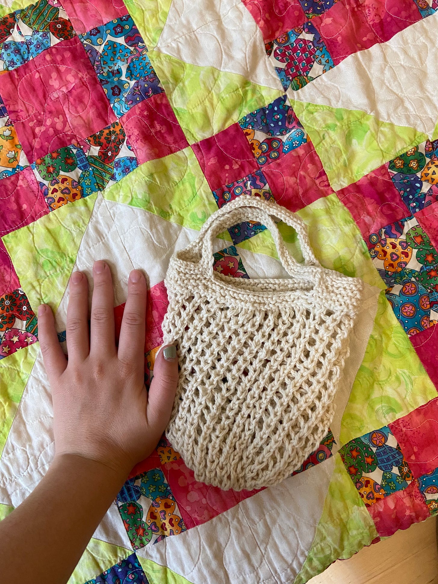 a knit white bag with a loose mesh body, the size of my hand.