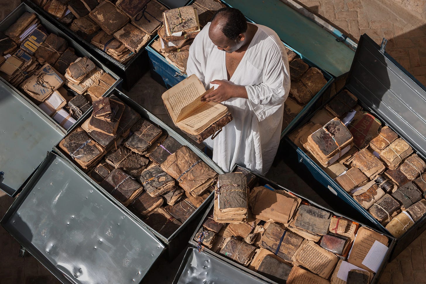 Picture of a man surrounded by lockers full of old-looking books, image taken from above