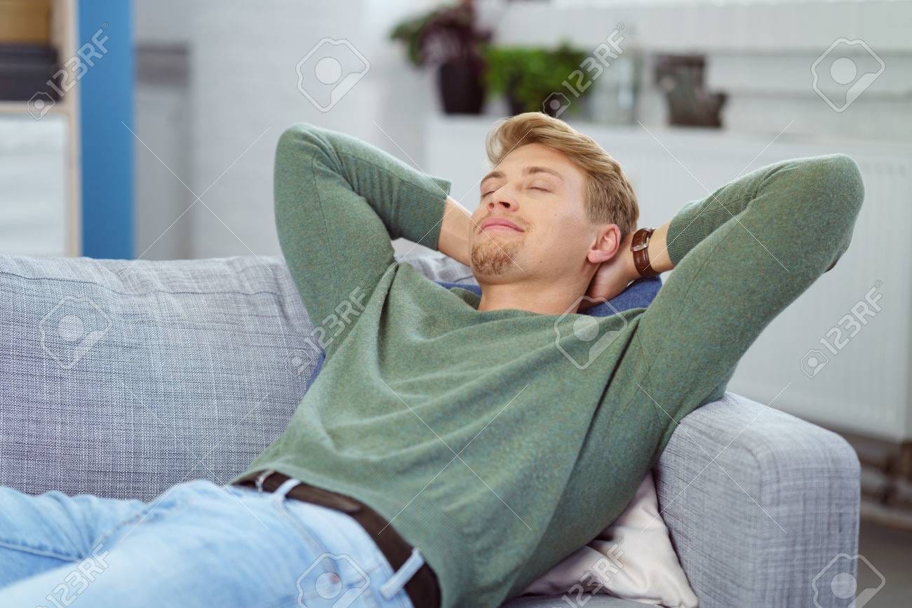 Young Man Relaxing On A Sofa With His Hands Clasped Behind His Head And  Eyes Closed Stock Photo, Picture And Royalty Free Image. Image 58547712.