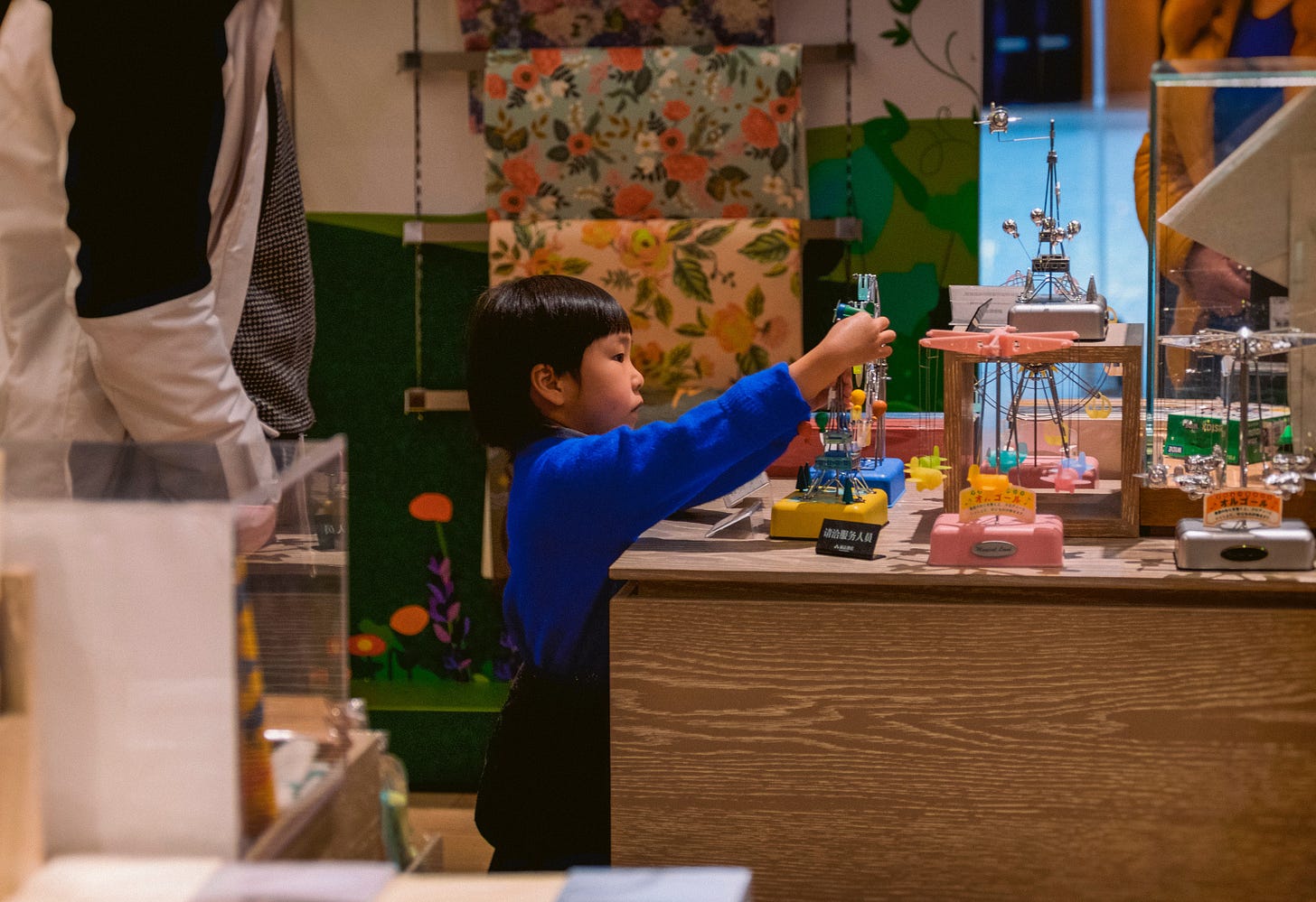  boy in blue long sleeve shirt standing beside brown wooden table