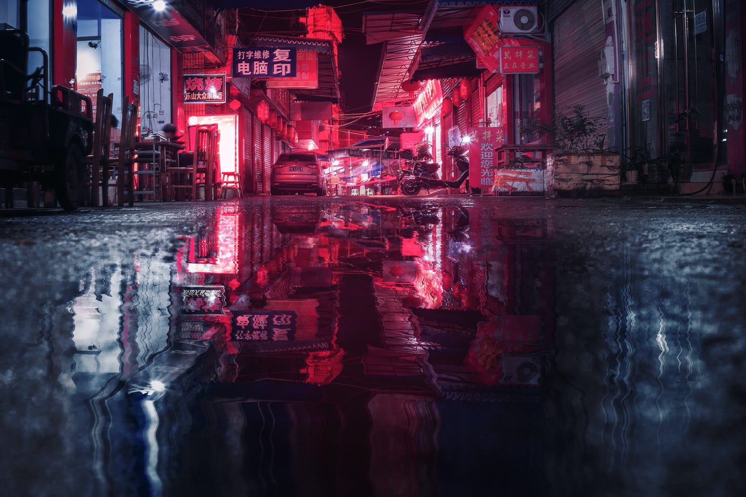 An alley downtown at night illuminated by red neon.