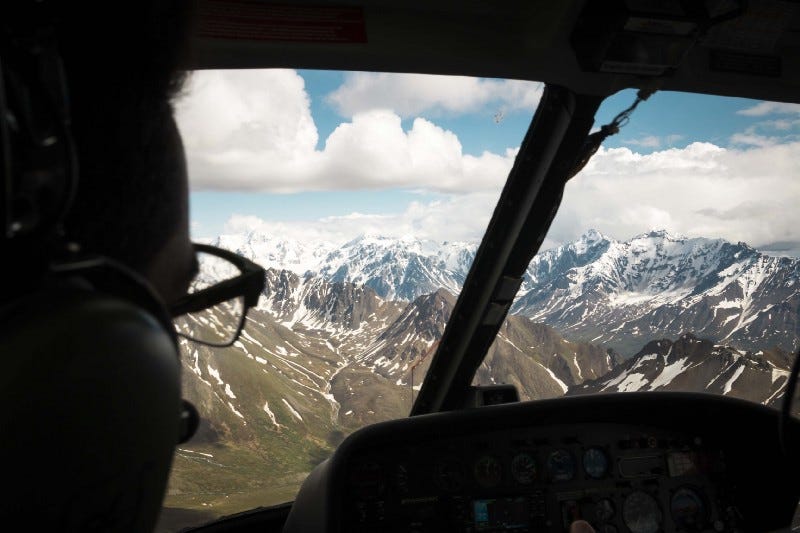 A plane pilot looking over a landscape of mountains and clouds