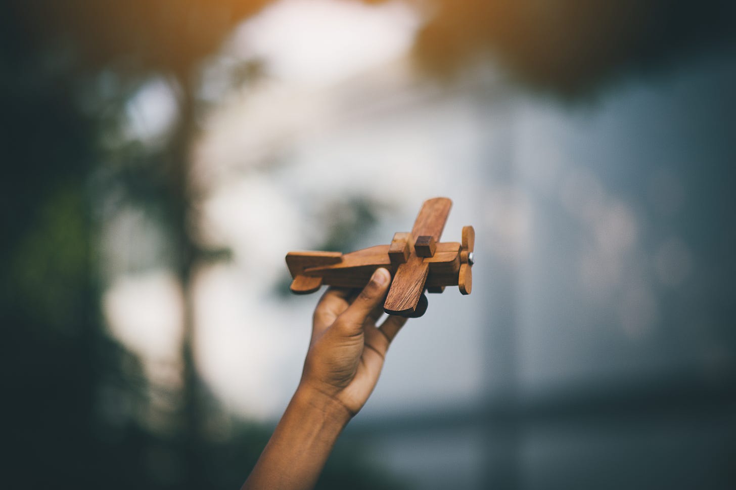 A child's hand holding a very rudimentary toy wooden plane