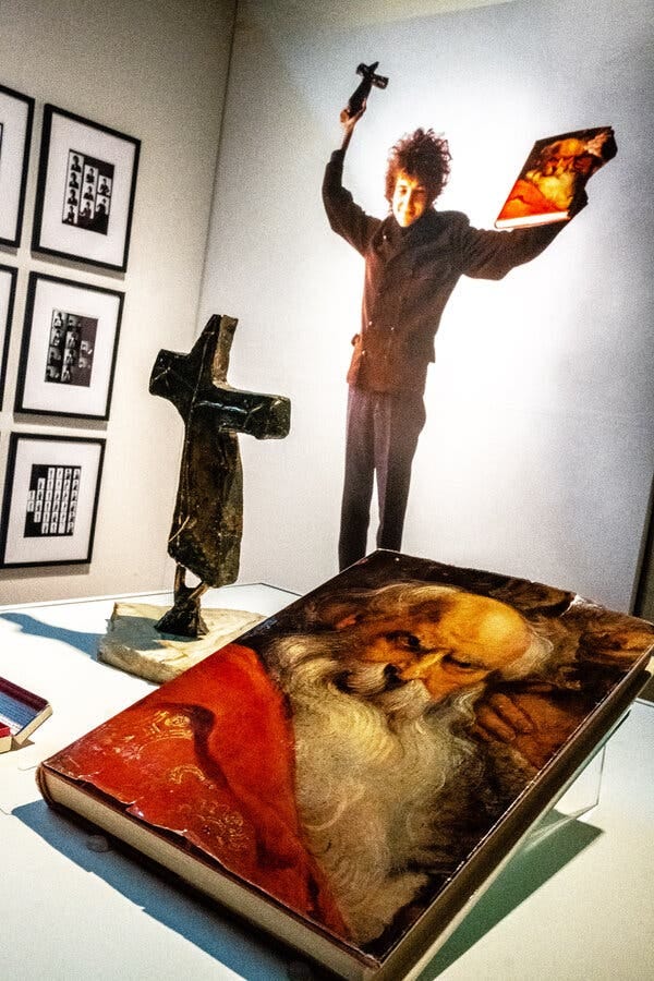 Original props belonging to the photographer Jerry Schatzberg sit before a photograph of Dylan holding them during a photoshoot.