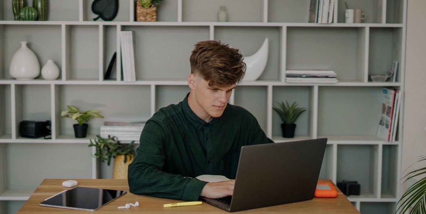Young man in a green long-sleeve shirt looking at his laptop